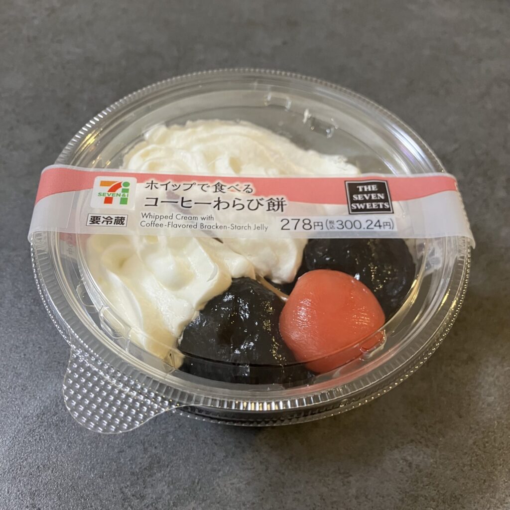 セブンイレブンの「ホイップで食べる コーヒーわらび餅」、ネーミングに惹かれてつい手が伸びたスイーツです！ 見た目はレトロかわいく、黒々としたコーヒー風味のわらび