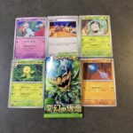 セブンイレブンでゲットした「変幻の仮面」パックから現れたチリーンのカード。まず目を引くのは、色鮮やかでどこかレトロな夏祭りのような背景。 風鈴のように揺れるチリ